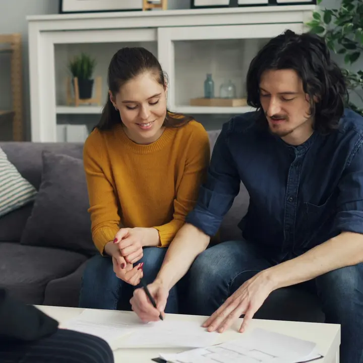 Couple signing an agreement with a salesperson, the moment a lead becomes a sale