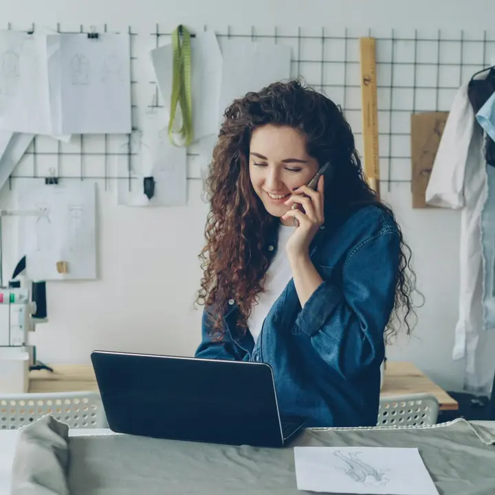 Shop owner answering a customer phone call at her workshop table