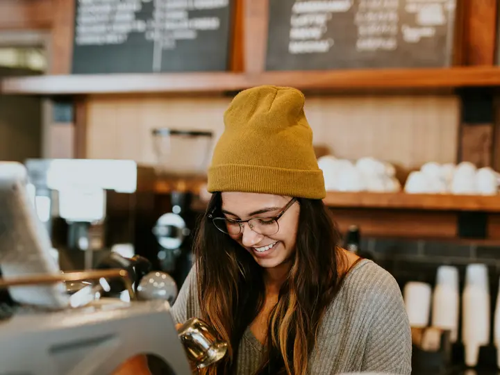 Smiling barista serving a regular customer at a coffee shop counter