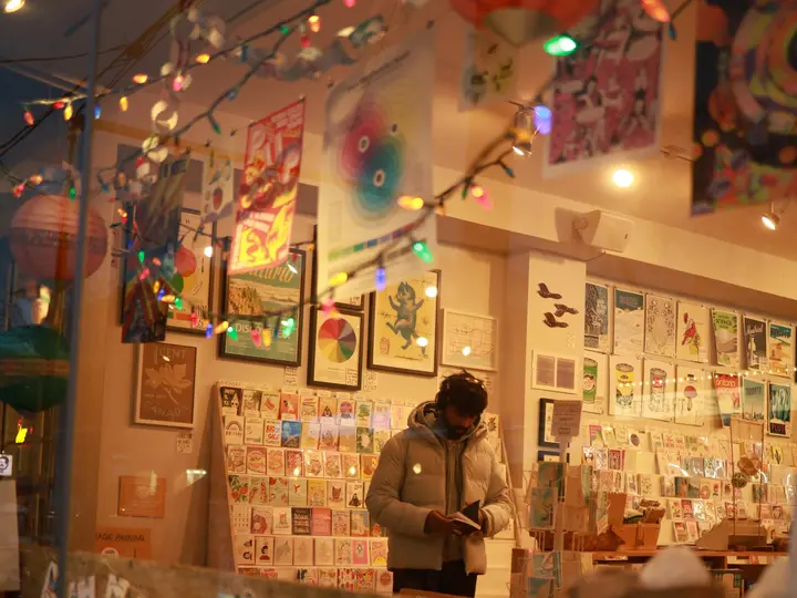 Shop owner arranging greeting cards in a festive independent gift shop