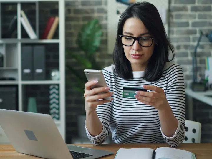 Woman holding a credit card while finishing an online order on her phone