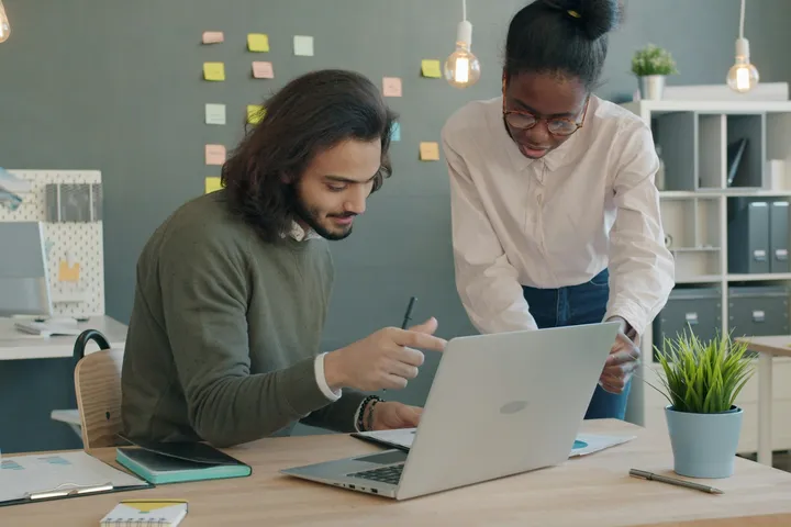 Two marketing strategists reviewing a campaign together at a laptop
