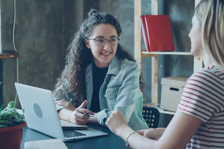 Marketing strategist talking through a plan with a business owner at a laptop