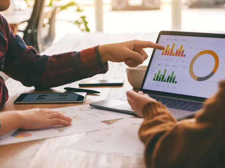 Strategist pointing at campaign performance charts on a laptop during a review