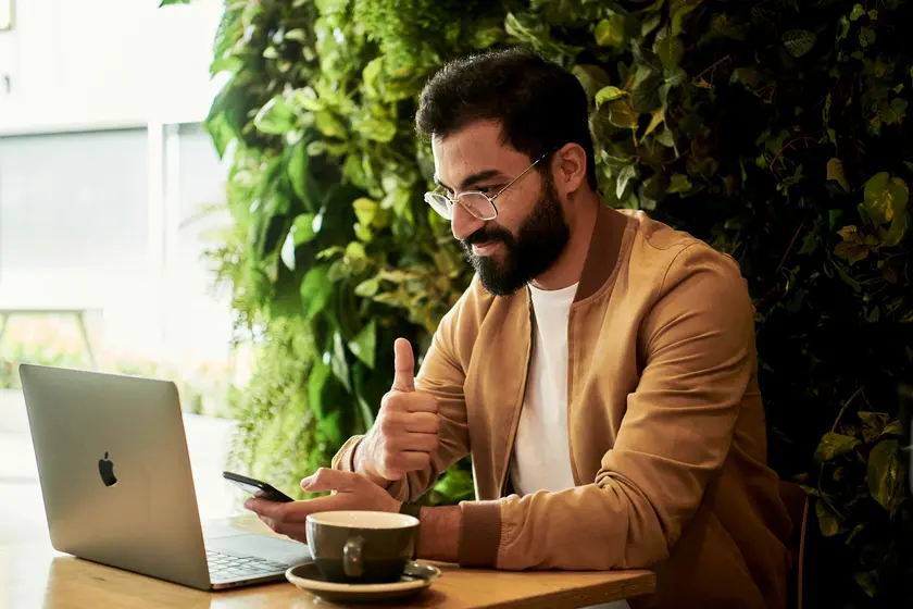 Business owner smiling while reviewing new customer leads on a laptop in a cafe