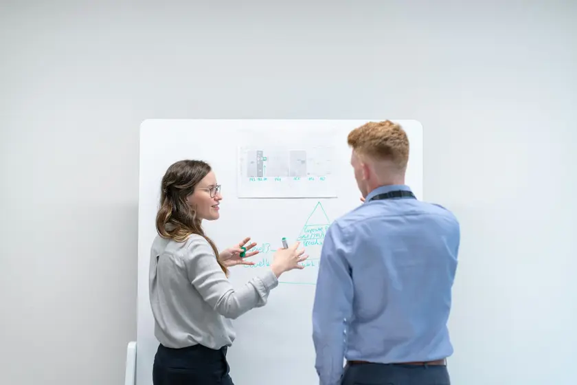 Consultant mapping a sales process on a whiteboard with a client