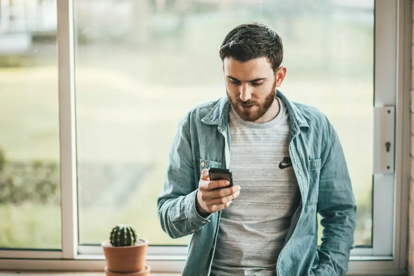 Customer reading an email on his phone while standing by a window