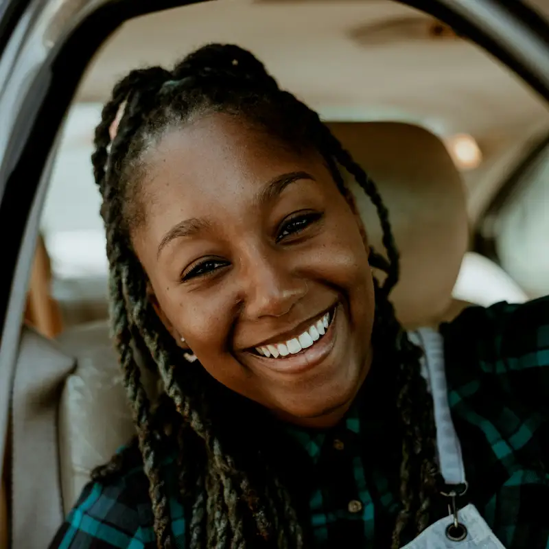 Email header photo: a smiling woman in a plaid shirt sitting in the driver’s seat of her car
