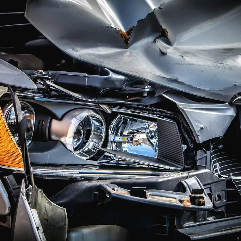 Email header photo: the front corner of a silver car after a crash, with a buckled hood and a broken headlight housing