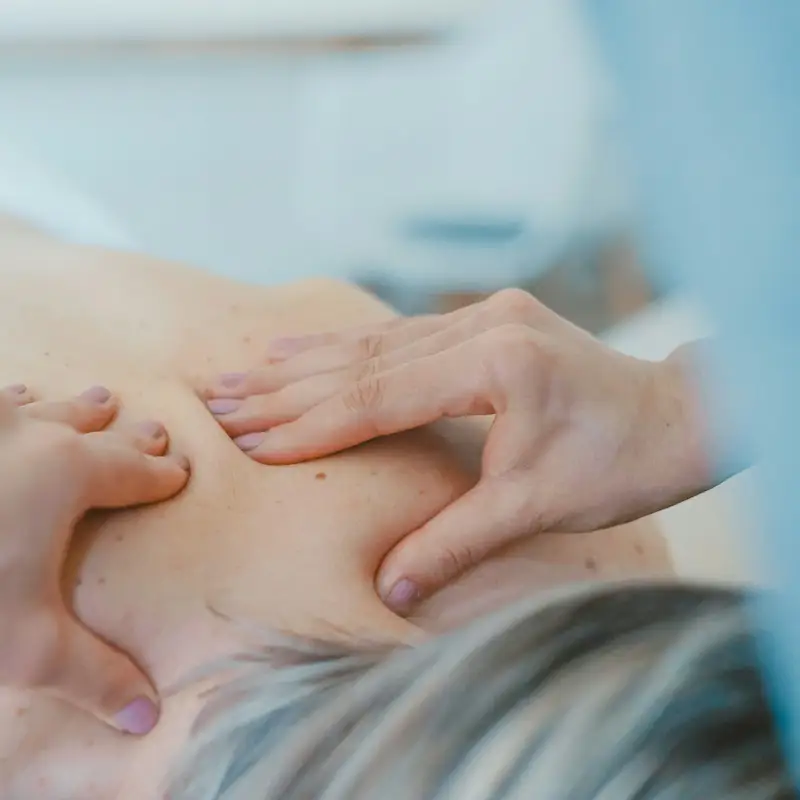 Email header photo: massage therapist working on a client’s upper back and shoulder with both hands