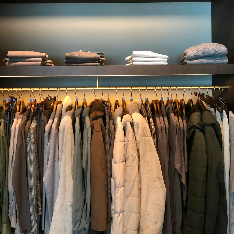 Email header photo: a tidy closet with folded sweaters spaced evenly on a lit shelf above a rail of jackets on matching wooden hangers