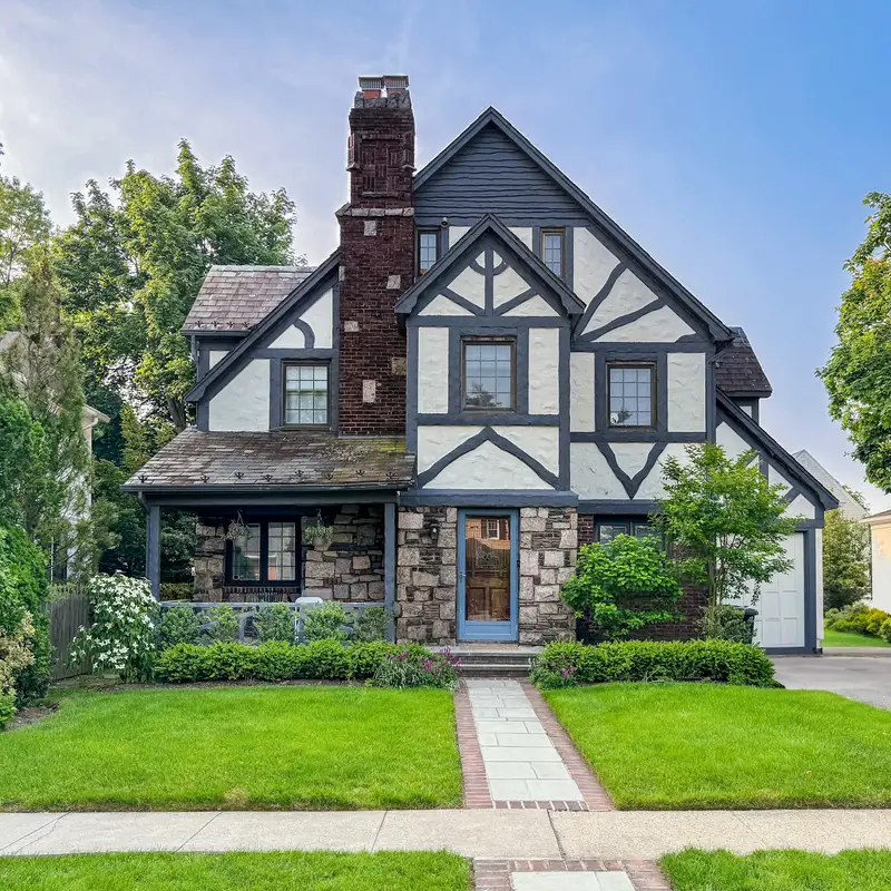 Email header photo: a tudor-style home with a stone chimney, crisp white and dark trim and a bright, clean front walk and driveway