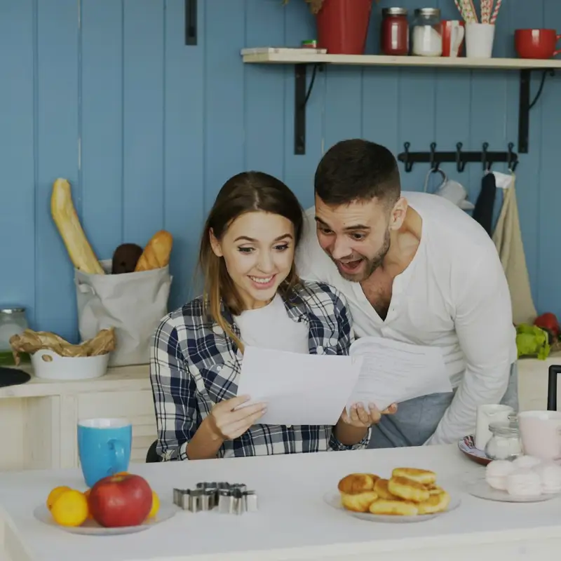 Email header photo: an excited couple reading a printed document together at their kitchen table