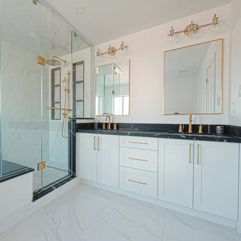 Email header photo: a remodeled bathroom with a glass walk-in shower and bench beside a white double vanity with brass fixtures