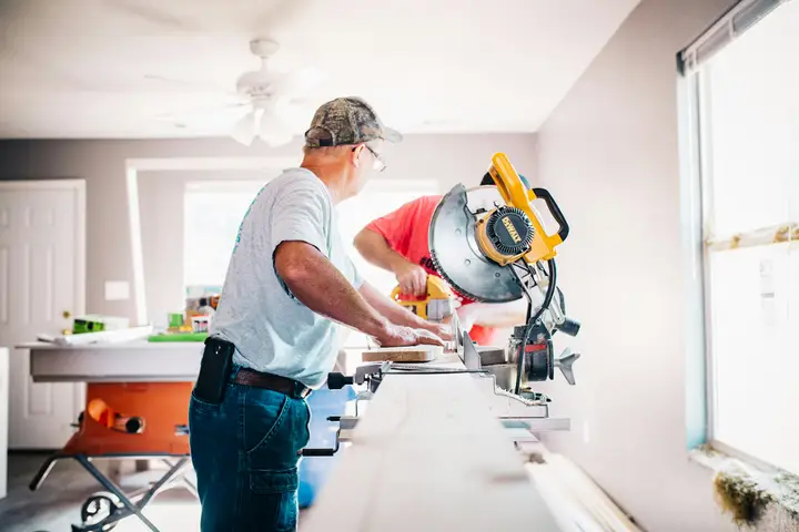 Remodeling contractor cutting trim at a miter saw inside a home