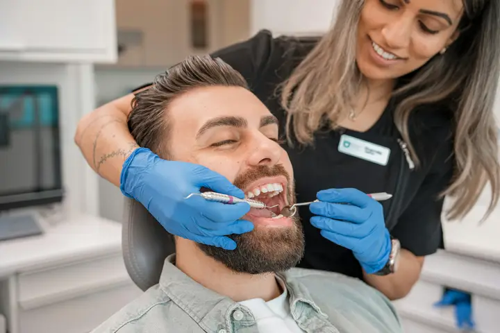 Dentist in blue gloves examining a patient in a dental chair