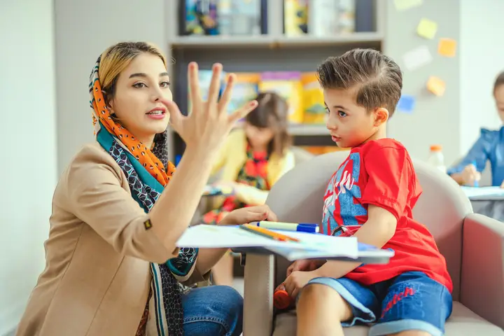 Teacher counting on her fingers with young students in a classroom