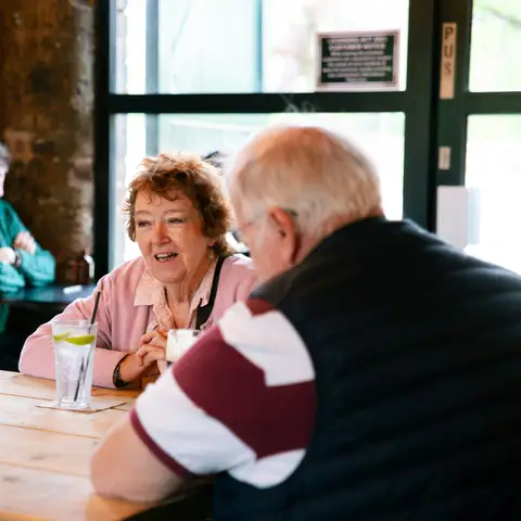 Two older couples talking and smiling together around a cafe table