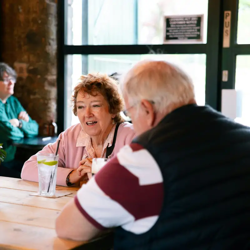Email header photo: two older couples talking and smiling together around a cafe table