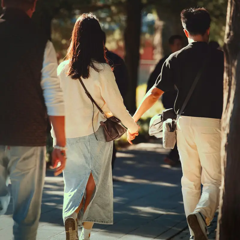 Email header photo: a woman and a man holding hands while walking along a sunlit path