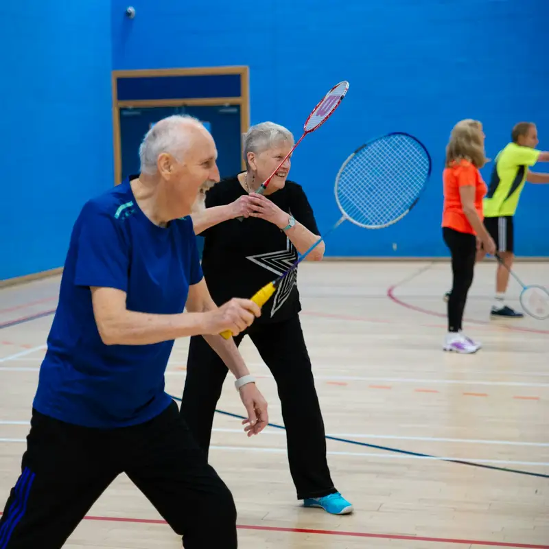 Email header photo: older adults playing a lively game of badminton in a sports hall