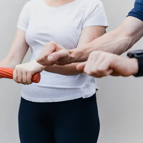 Physical therapist guiding a patient through a grip exercise with a resistance bar