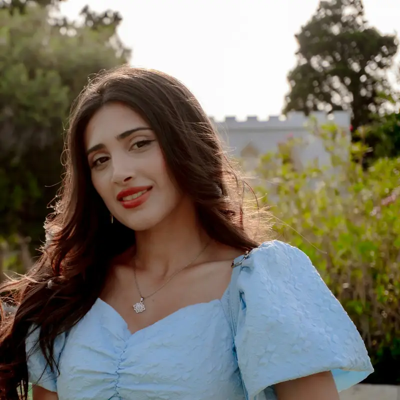 Email header photo: a smiling woman with long dark hair in a light blue dress outdoors on a sunny evening