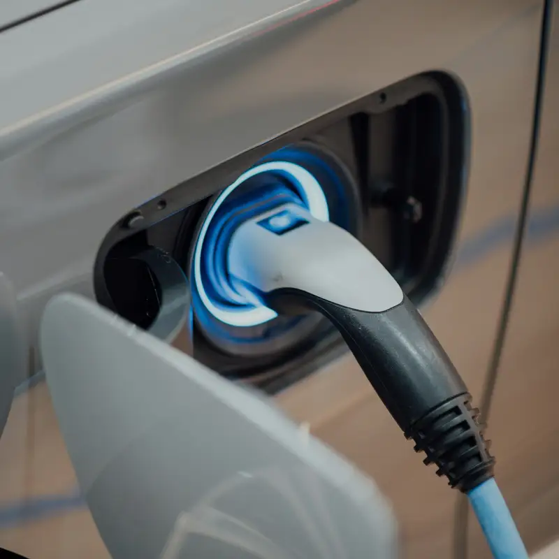 Email header photo: close-up of a charging cable plugged into an electric car, the charge port glowing blue