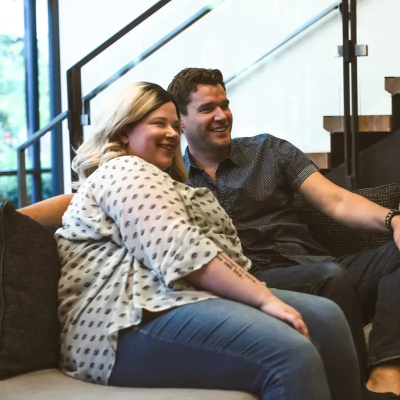 Email header photo: smiling couple relaxing on a sofa at home
