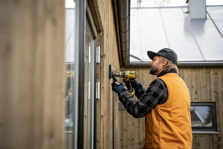 Home services technician in a work cap using a drill during a repair
