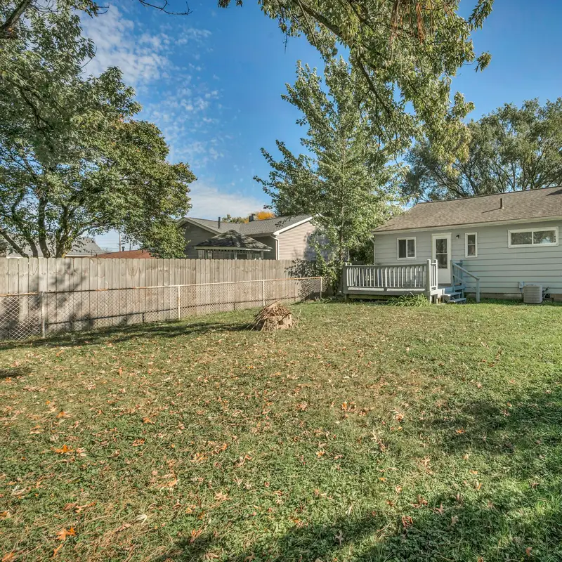 Email header photo: a wide, green backyard lawn behind a single-story gray house with a small deck, a wooden fence and tall shade trees