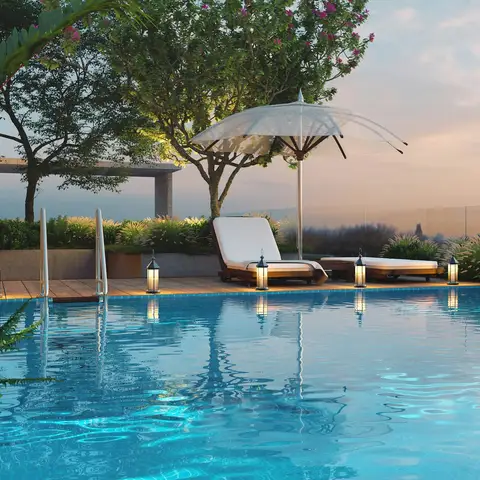 Hotel infinity pool with lounge chairs and a white umbrella at sunset
