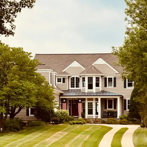 A freshly striped green front lawn beside a curving driveway leading to a large two-story house
