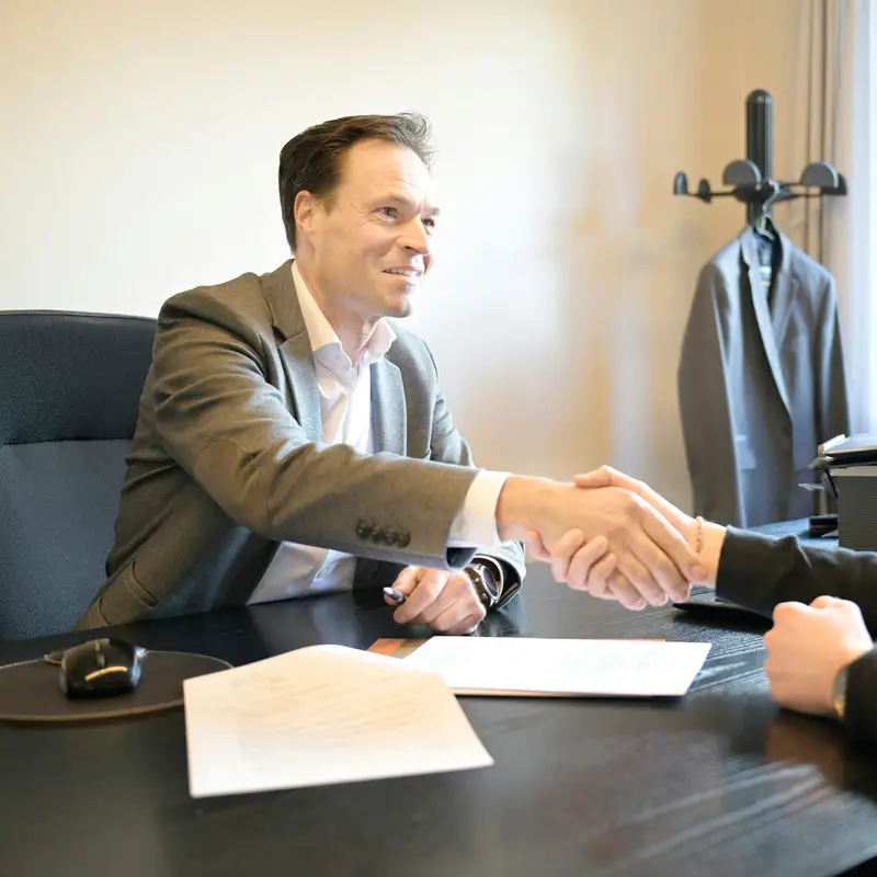 Email header photo: two smiling men shaking hands across an office desk