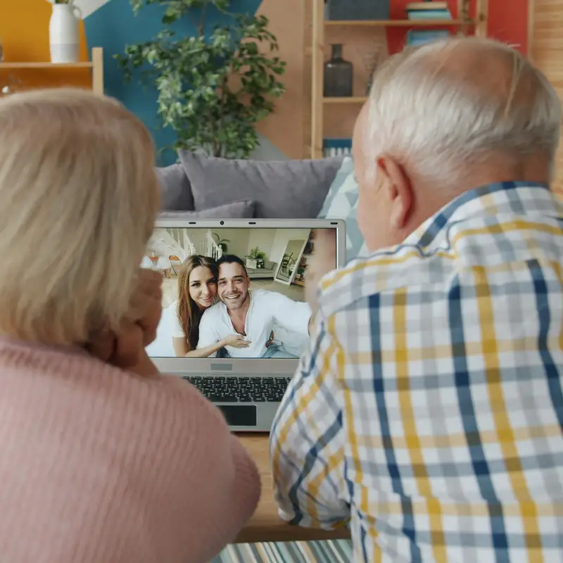 Email header photo: an older couple seen from behind on a video call with a smiling younger couple on the laptop screen