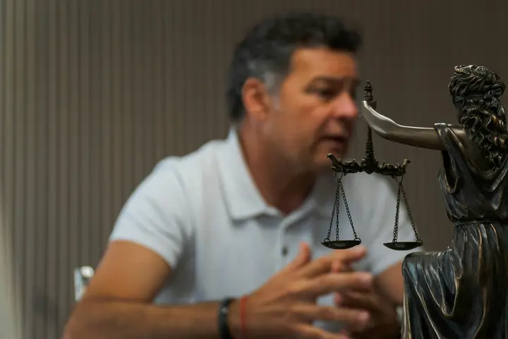 Attorney at a conference table beside a statue of Lady Justice