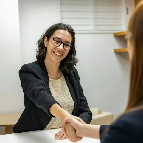 Attorney shaking hands with a client across a table at a consultation