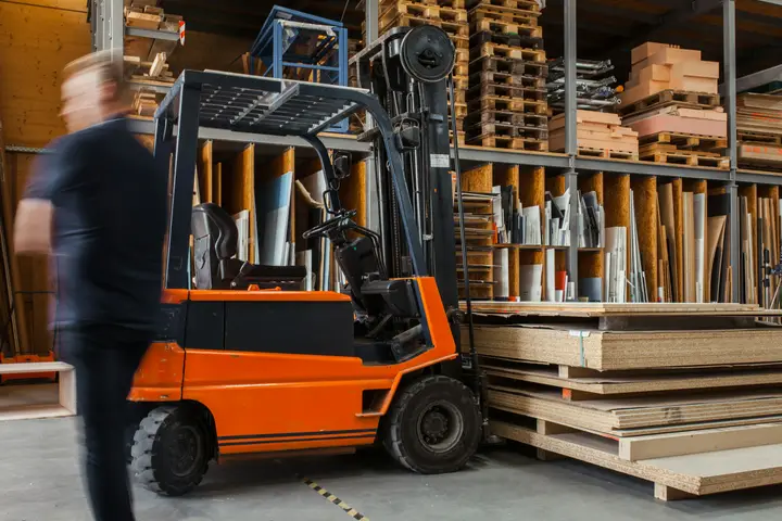 Forklift moving stacked materials inside a warehouse