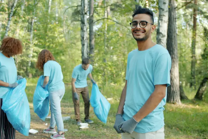 Volunteers with trash bags cleaning up a park together