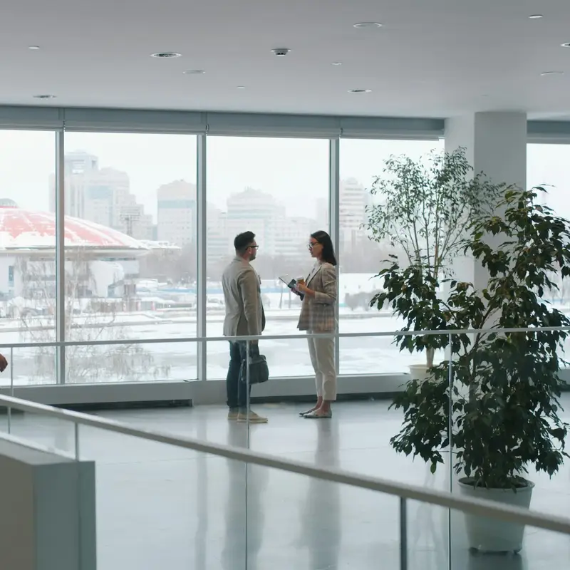 Email header photo: two people in business clothes talking on an empty office floor, with tall windows looking out over a snowy city