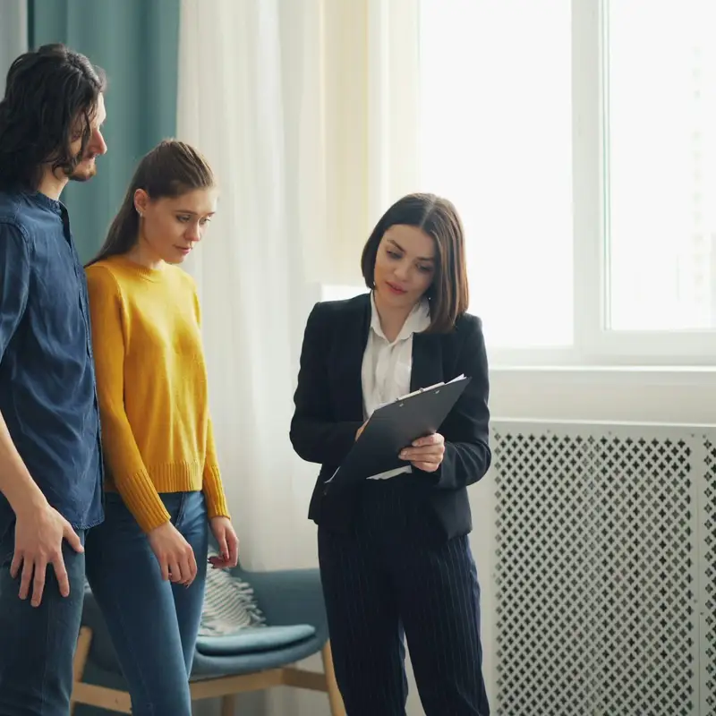 Email header photo: a young couple in a bright living room looking over a clipboard with a woman in a dark suit