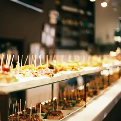 A long catered table of appetizer skewers and small bites lined up for guests at an evening event