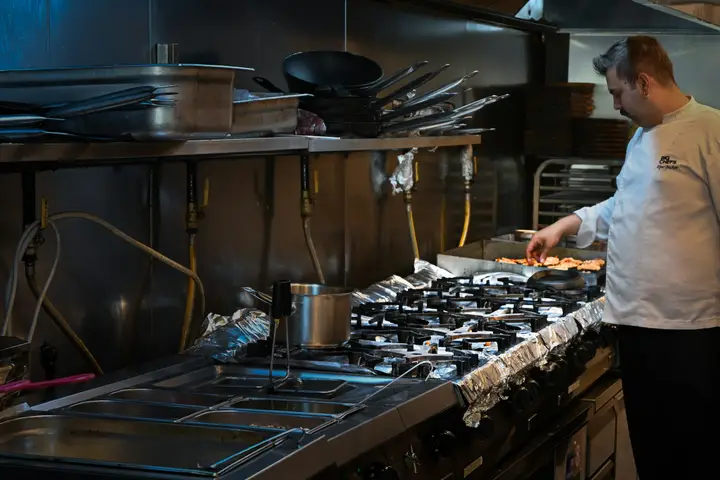 Chef cooking at the stove in a commercial restaurant kitchen