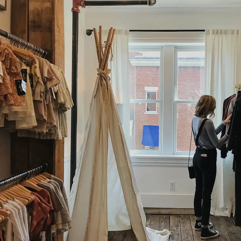 Email header photo: a woman looking through clothes on a rack in a boutique