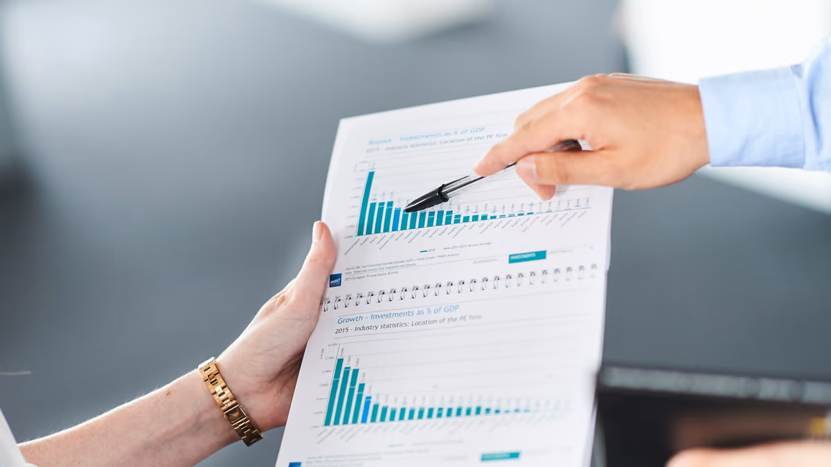 Two colleagues reviewing a printed report of bar charts, one pointing to the results with a pen