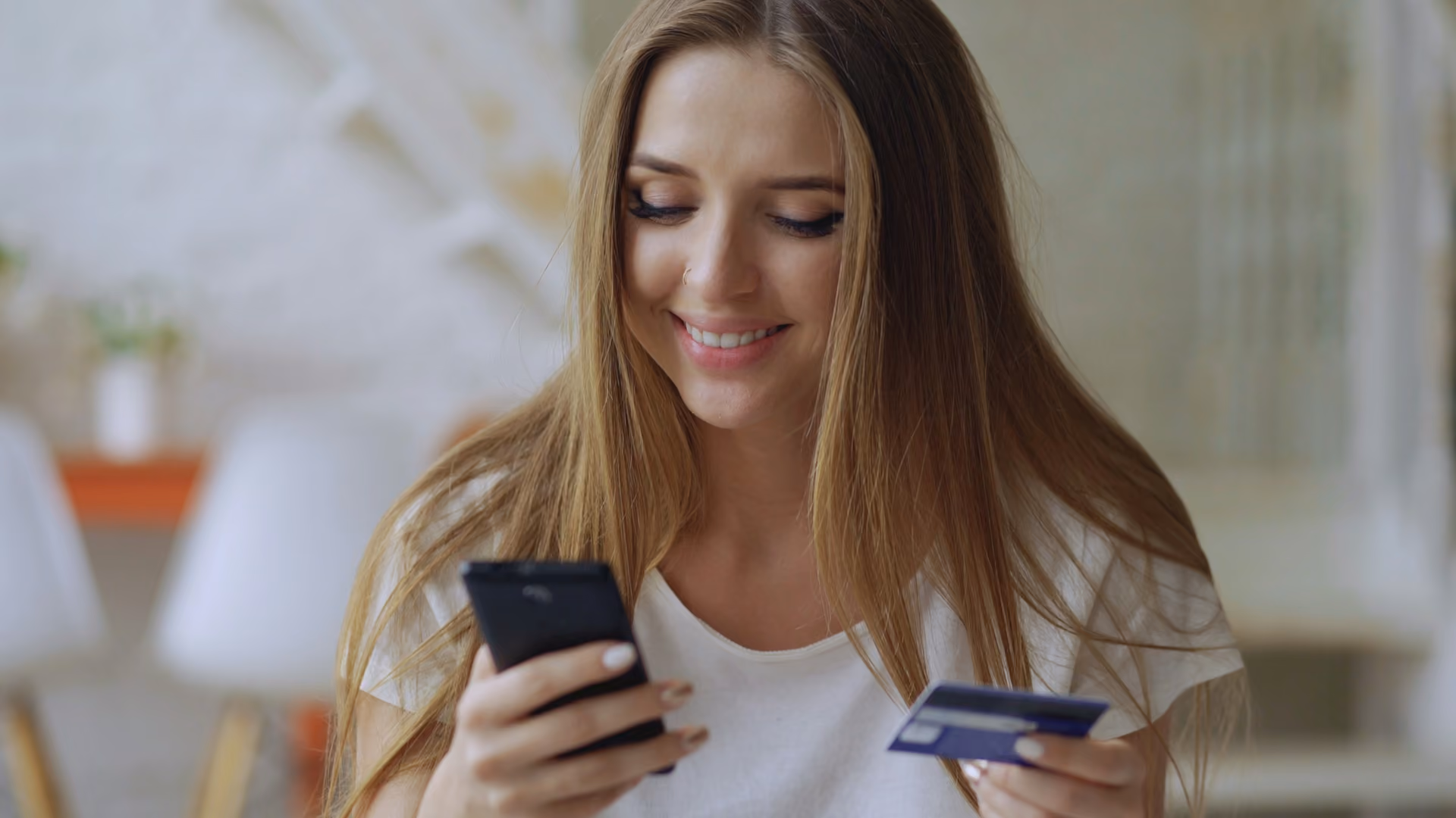Smiling shopper holding a smartphone and a credit card, about to complete a mobile checkout