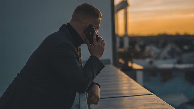 Business owner on a follow-up call with a new lead above the city at dusk