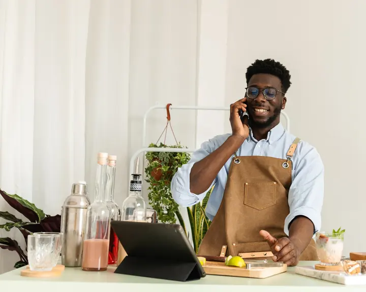 Shop owner smiling at his counter while taking a customer call