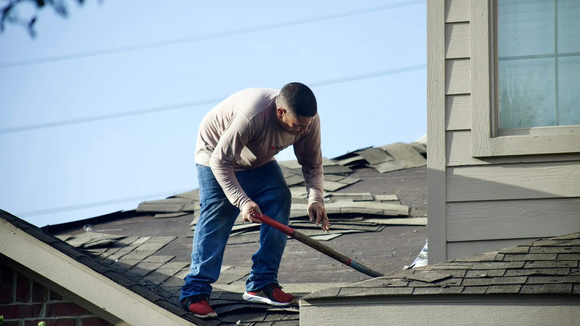 Roofer repairing shingles on the roof of a house
