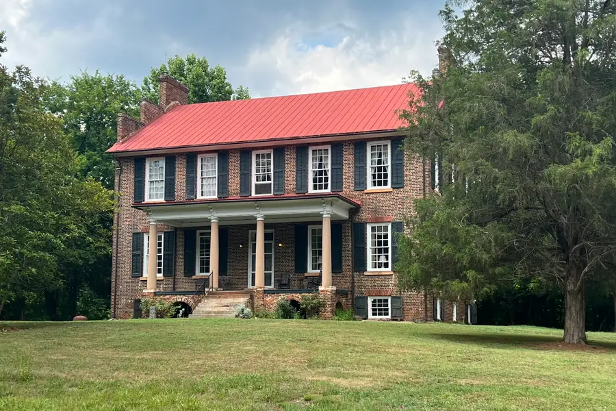 Cedar Grove, a two-story brick antebellum house with a red metal roof and white columned porch in Huntersville, North Carolina